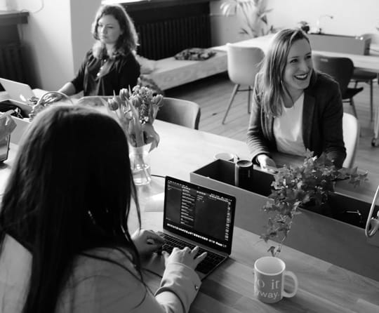 Women on laptops collaborating at work